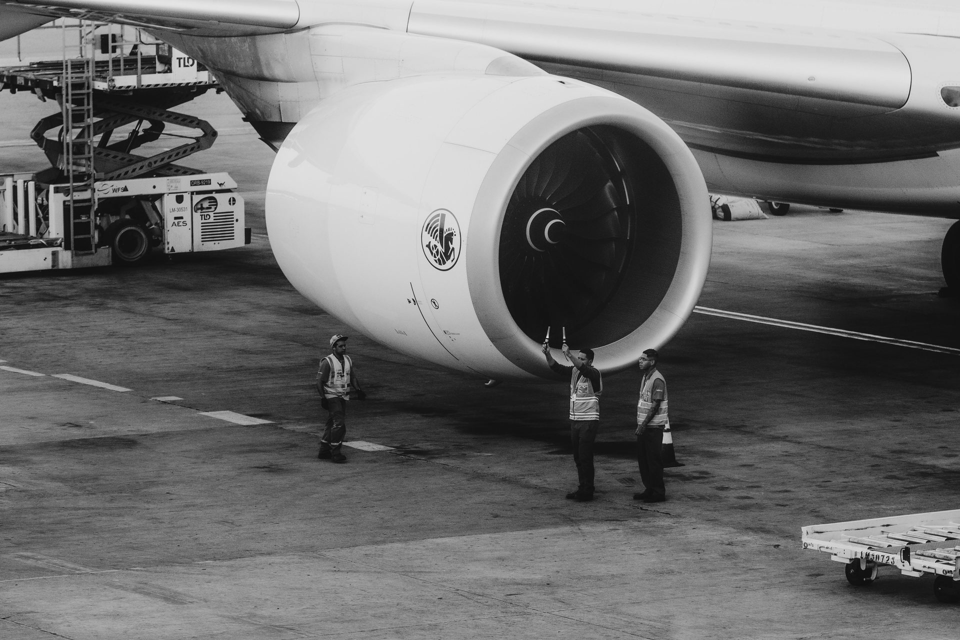 Ground crew inspecting a large turbofan engine on the tarmac during line maintenance